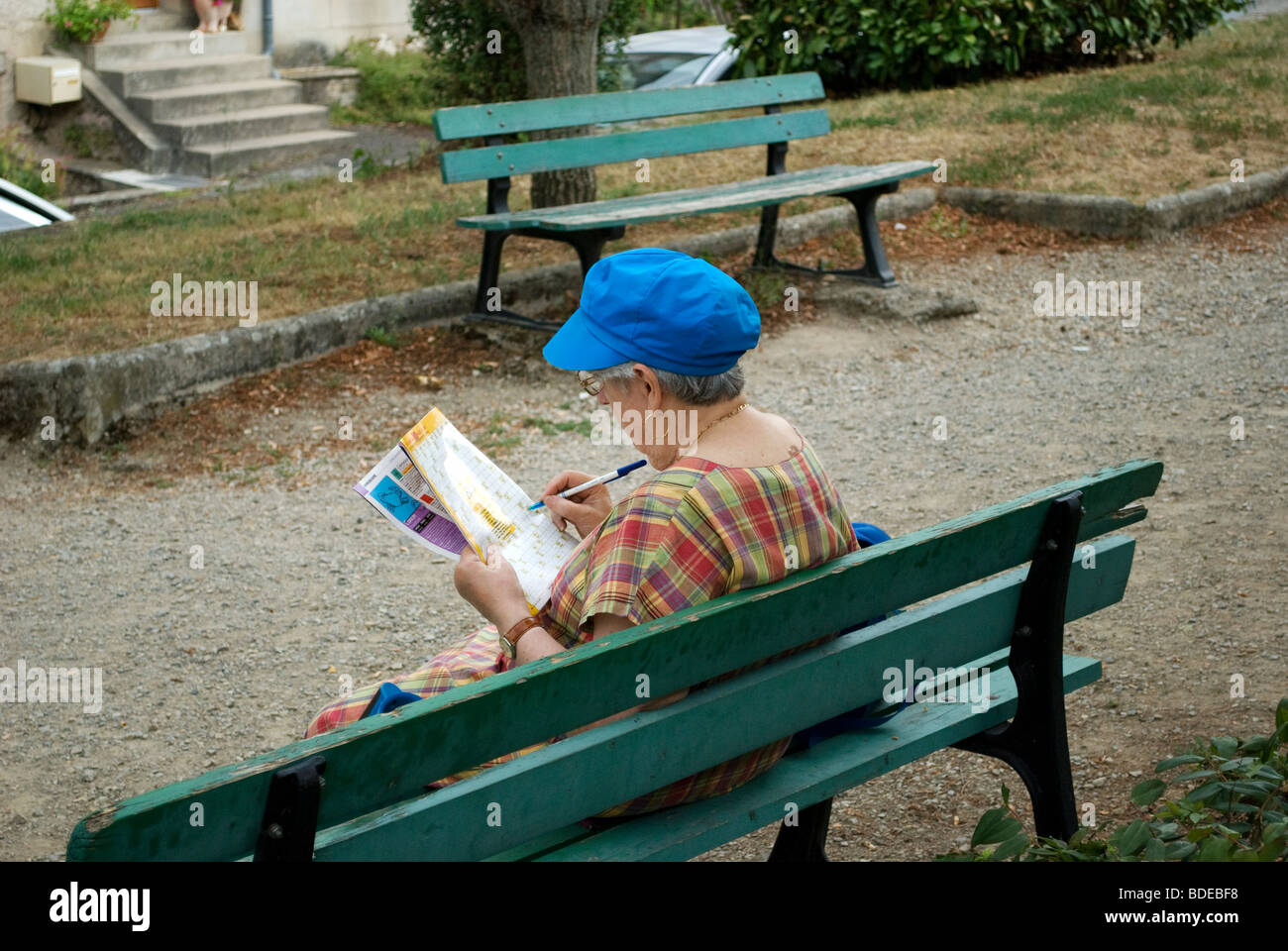 Signora seduta su una panchina facendo un puzzle in un magazzino, Najac, Francia. Foto Stock