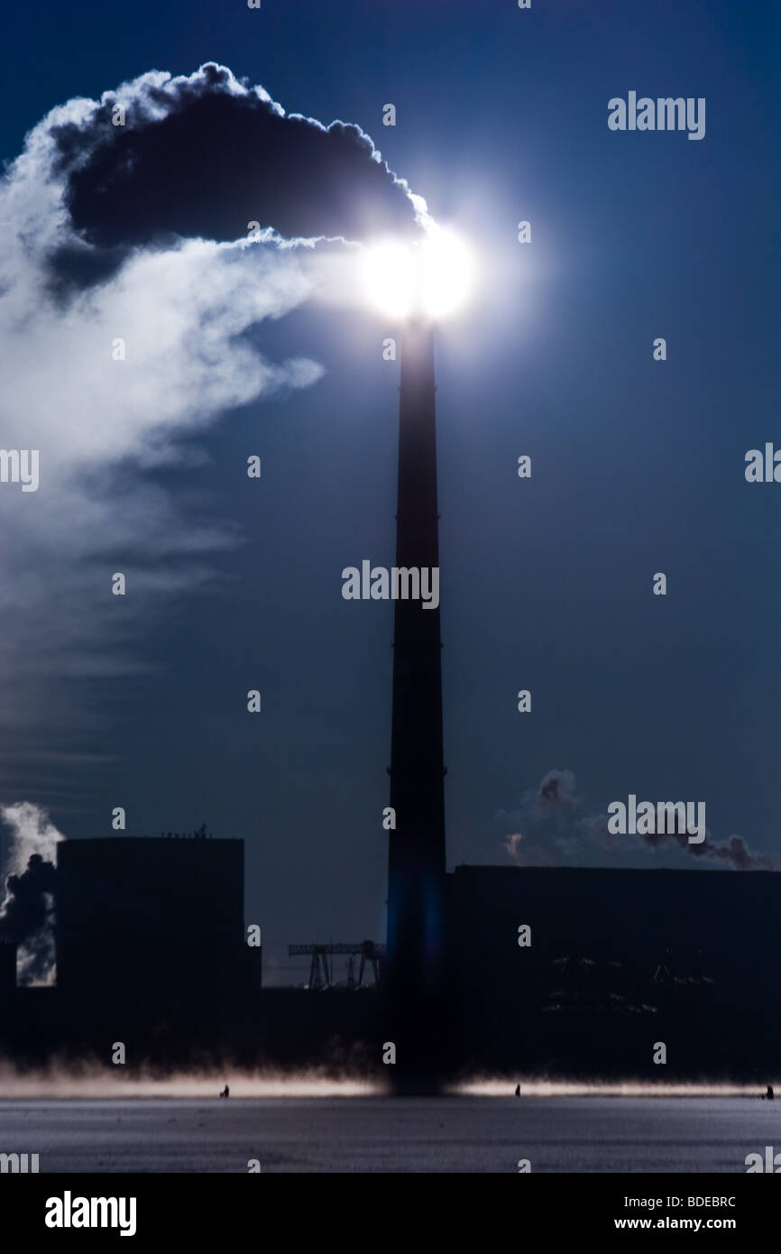 Il sole splende attraverso un fumo lasciando un tubo Foto Stock