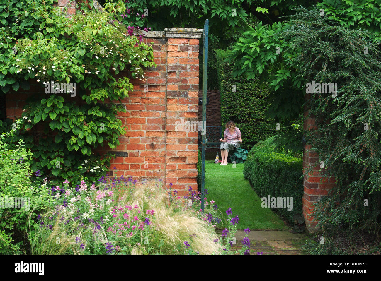 Lady artista che lavora su una pittura acquerello nei giardini di Cottesbrooke Hall, Northamptonshire, Regno Unito Foto Stock