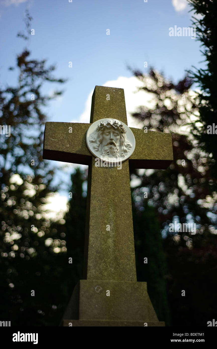 Foto scure della croce con la scultura di Gesù su un cimitero Foto Stock