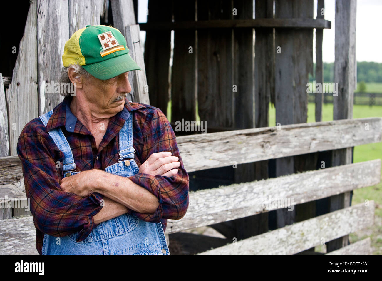 Senior uomo in piedi vicino a fienile con espressione seria sul viso Foto Stock