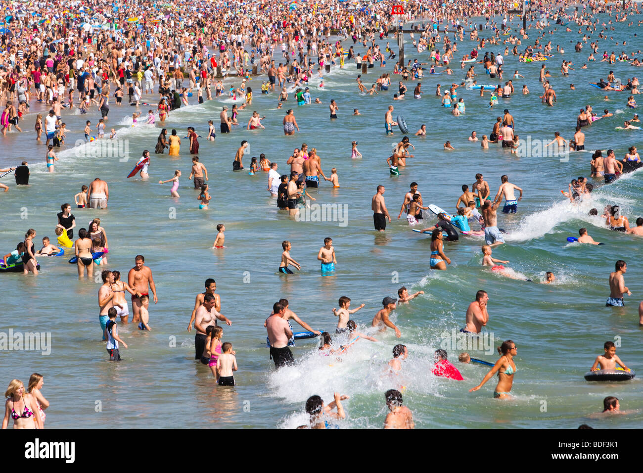 Spiaggia affollata e molti nuotatori in mare a Bournemouth, Regno Unito Foto Stock