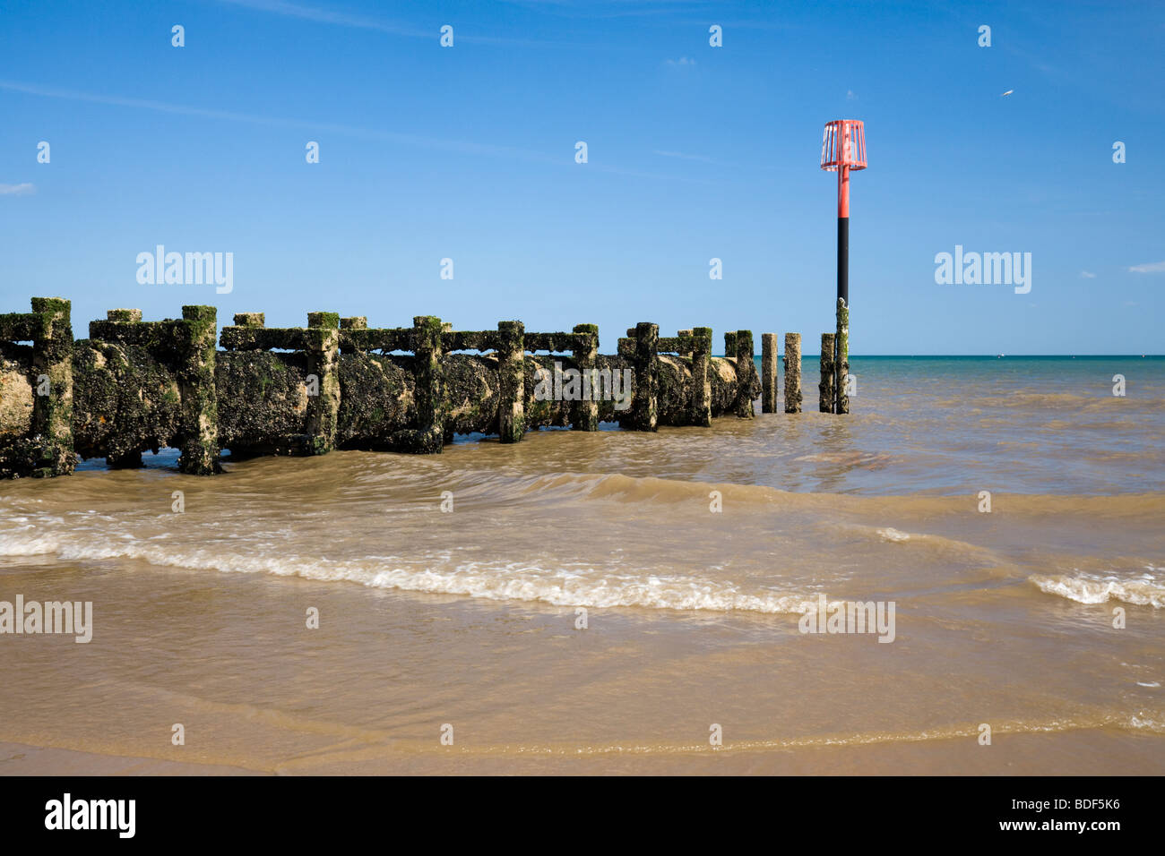 Pennelli correndo giù nel mare coperto di alghe e patelle su Bridlington North Beach come onde venire a riva. Foto Stock