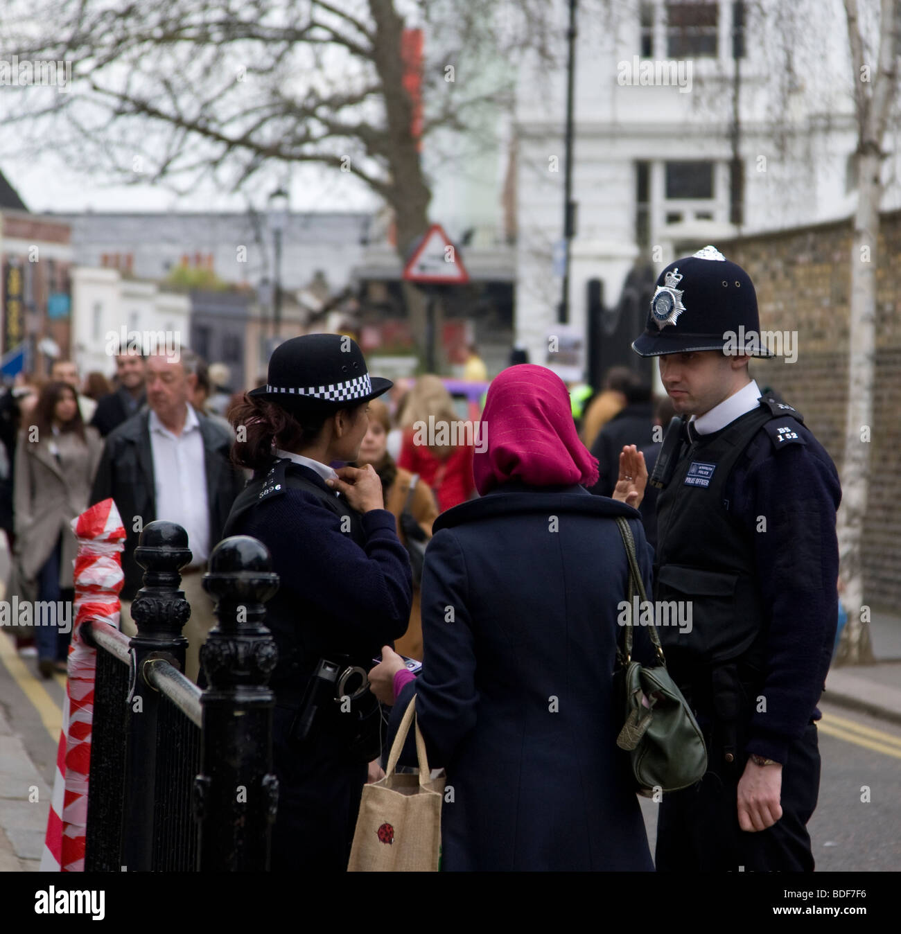 Maschio e femmina degli ufficiali di polizia aiutando un membro del pubblico in una strada vicino al Mercato di Portobello Road Foto Stock