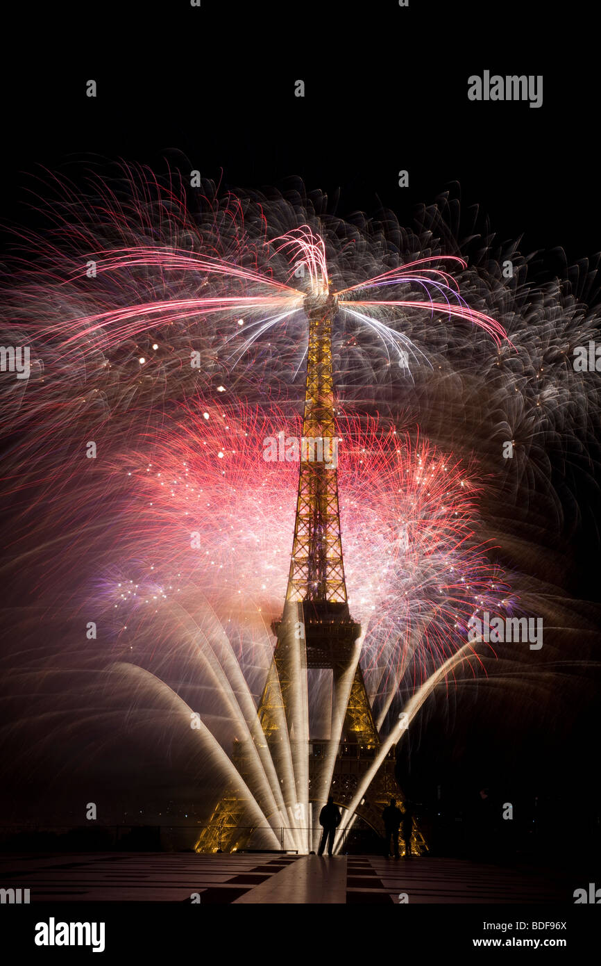 Il giorno della Bastiglia fuochi d'artificio Torre Eiffel Parigi Francia celebrazione di indipendenza piccole silhouette gendarme a base torre aggiunge prospettiva Foto Stock
