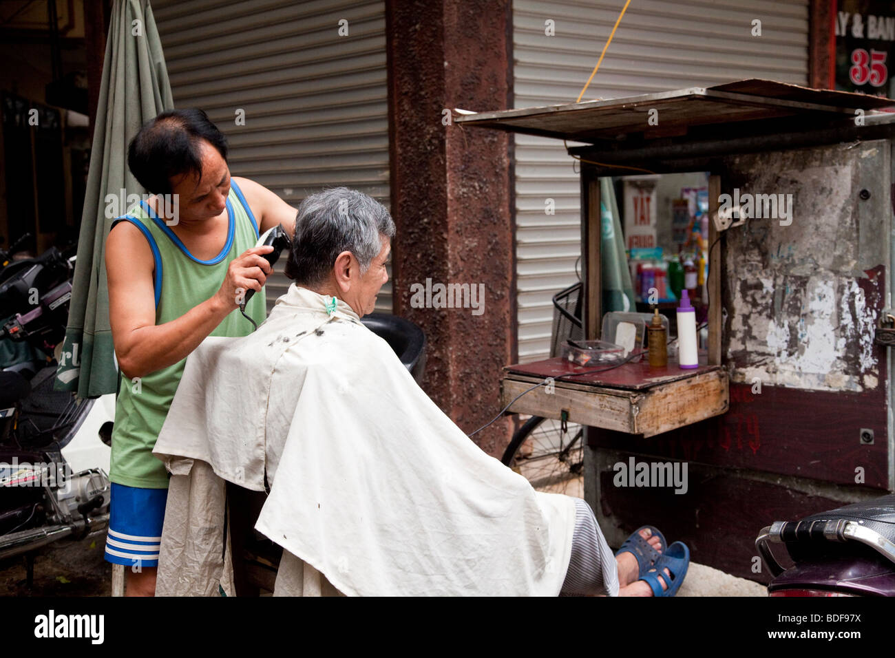 Un barbiere di strada nel quartiere vecchio, Hanoi, Vietnam Foto Stock