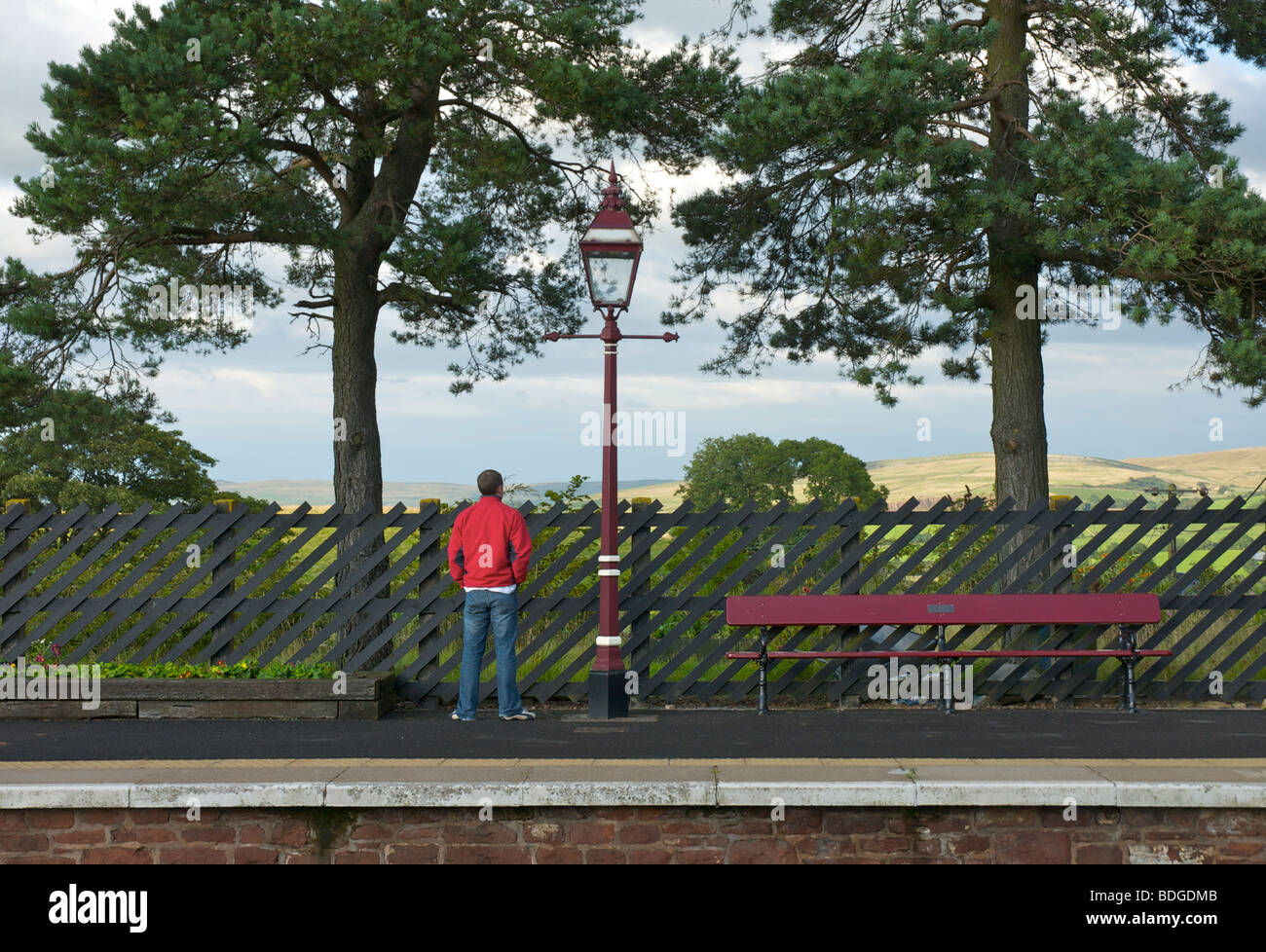 Uomo in attesa di un treno a Kirkby Stephen stazione ferroviaria sulla linea Settle-Carlisle, Cumbria, England Regno Unito Foto Stock