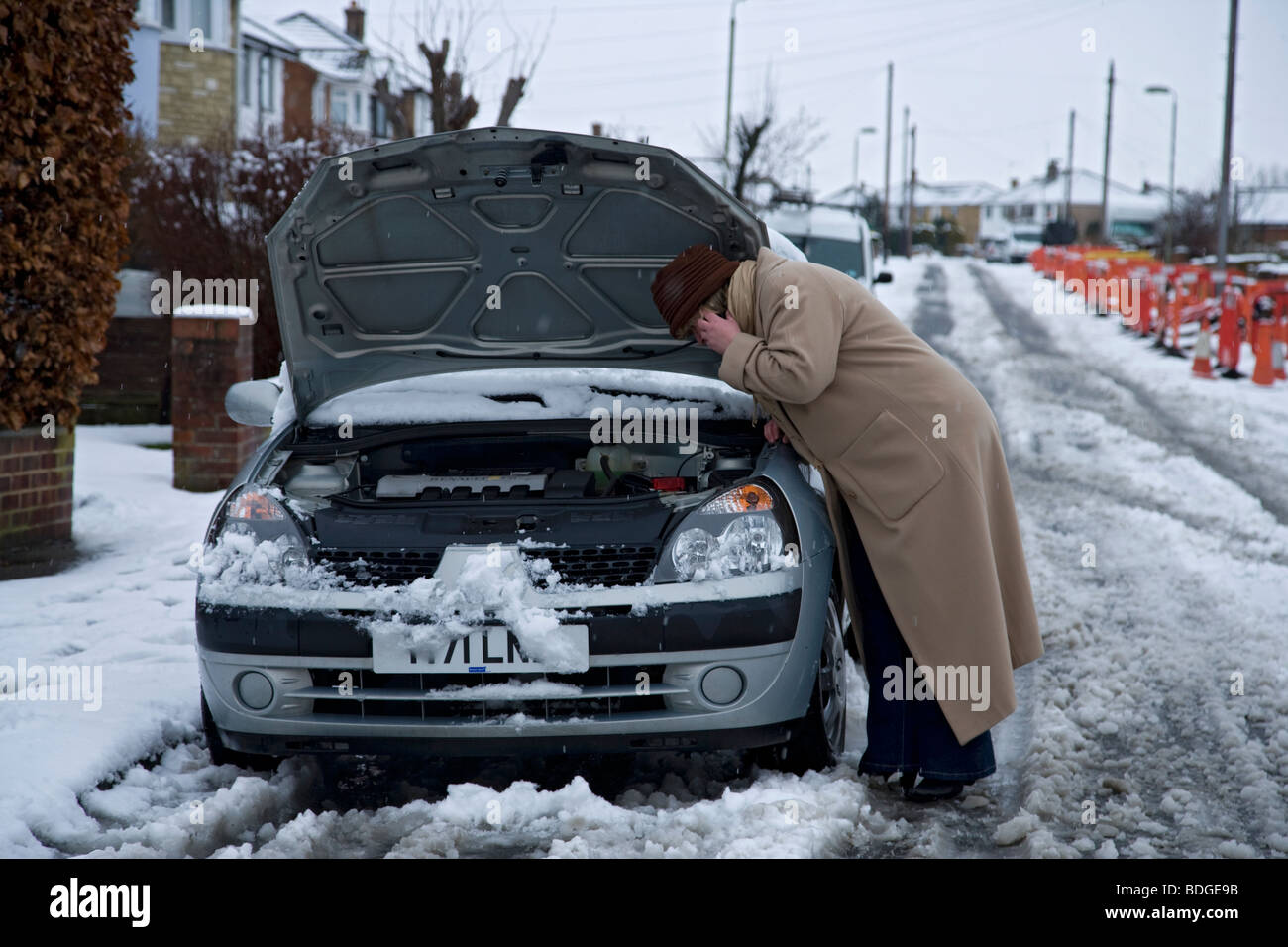Le donne sul suo proprio con ripartiti in auto in inverno la neve, cofano fino sul telefono cellulare di servizio recupero RIPARTIZIONE Foto Stock