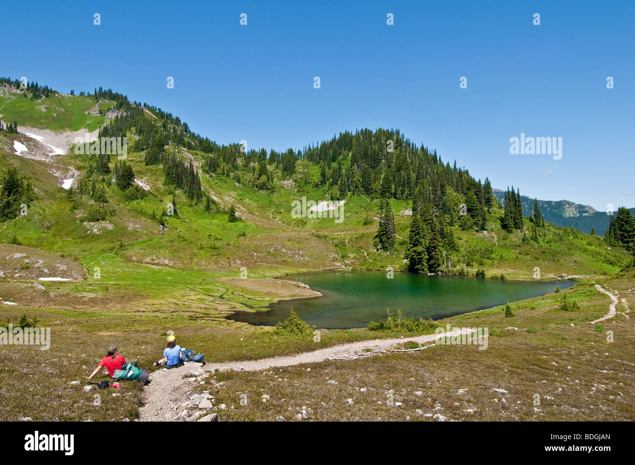 Due donne gli escursionisti avente il pranzo al Lago di cuore; Alta Divide Trail, il Parco Nazionale di Olympic, Washington. Foto Stock