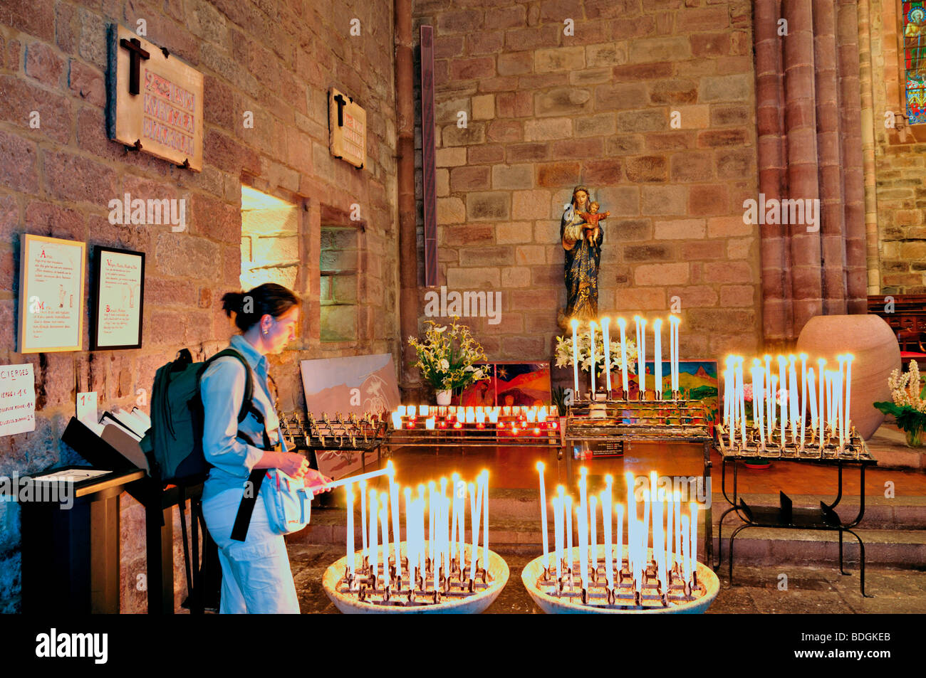 Francia, St. James Titolo: Donna candela che brucia nella chiesa parrocchiale Eglise Notre Dame Foto Stock