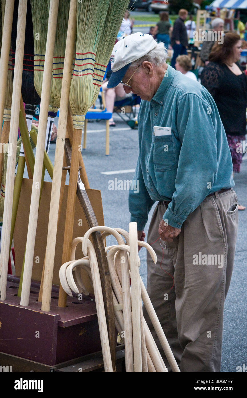 Un anziano, senior citizen visualizza in legno fatti a mano canne e scope Foto Stock