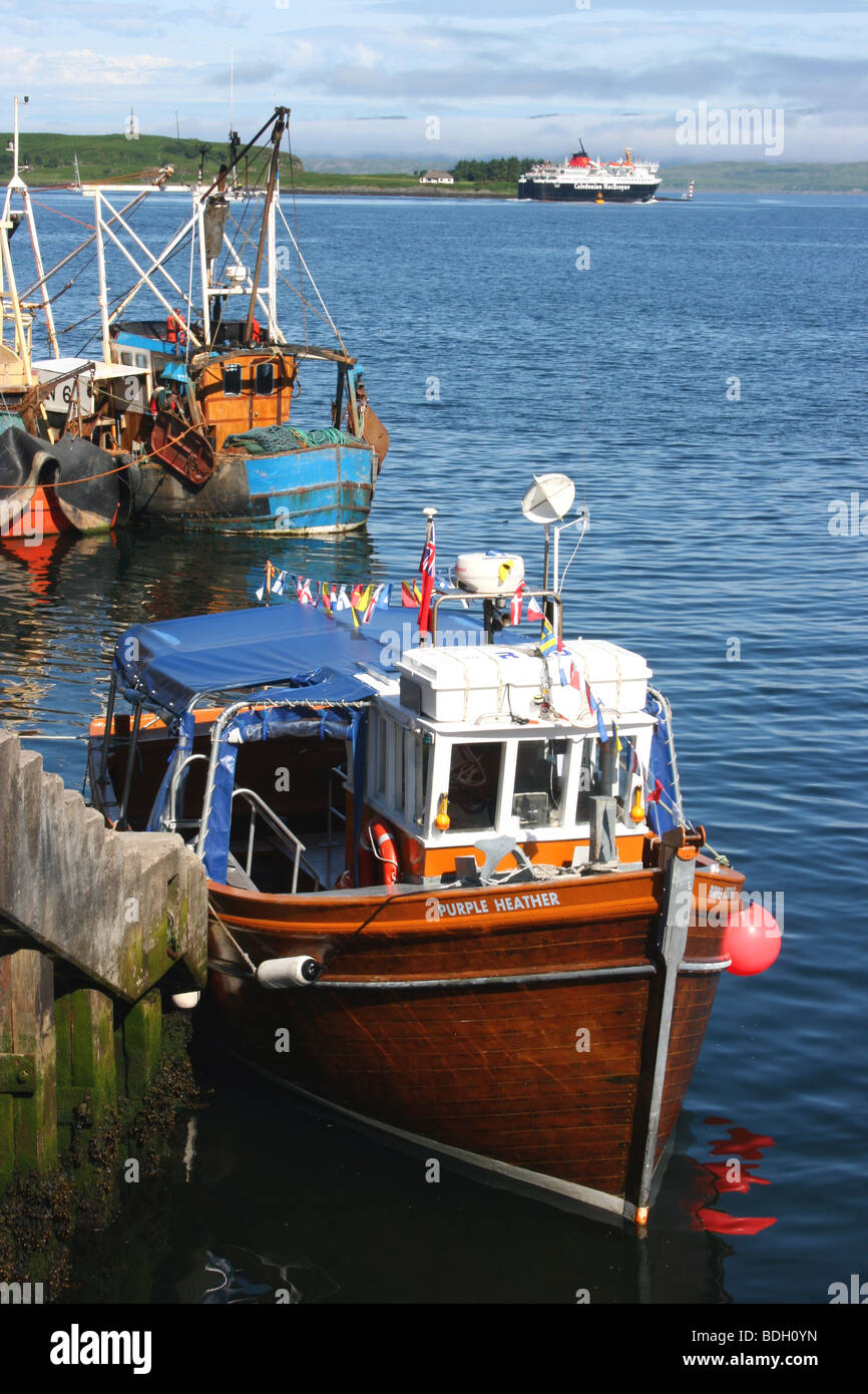 Imbarcazione da diporto ormeggiata presso la banchina nel porto di Oban, Argyll, Scozia occidentale, con il traghetto a Mull in background Foto Stock