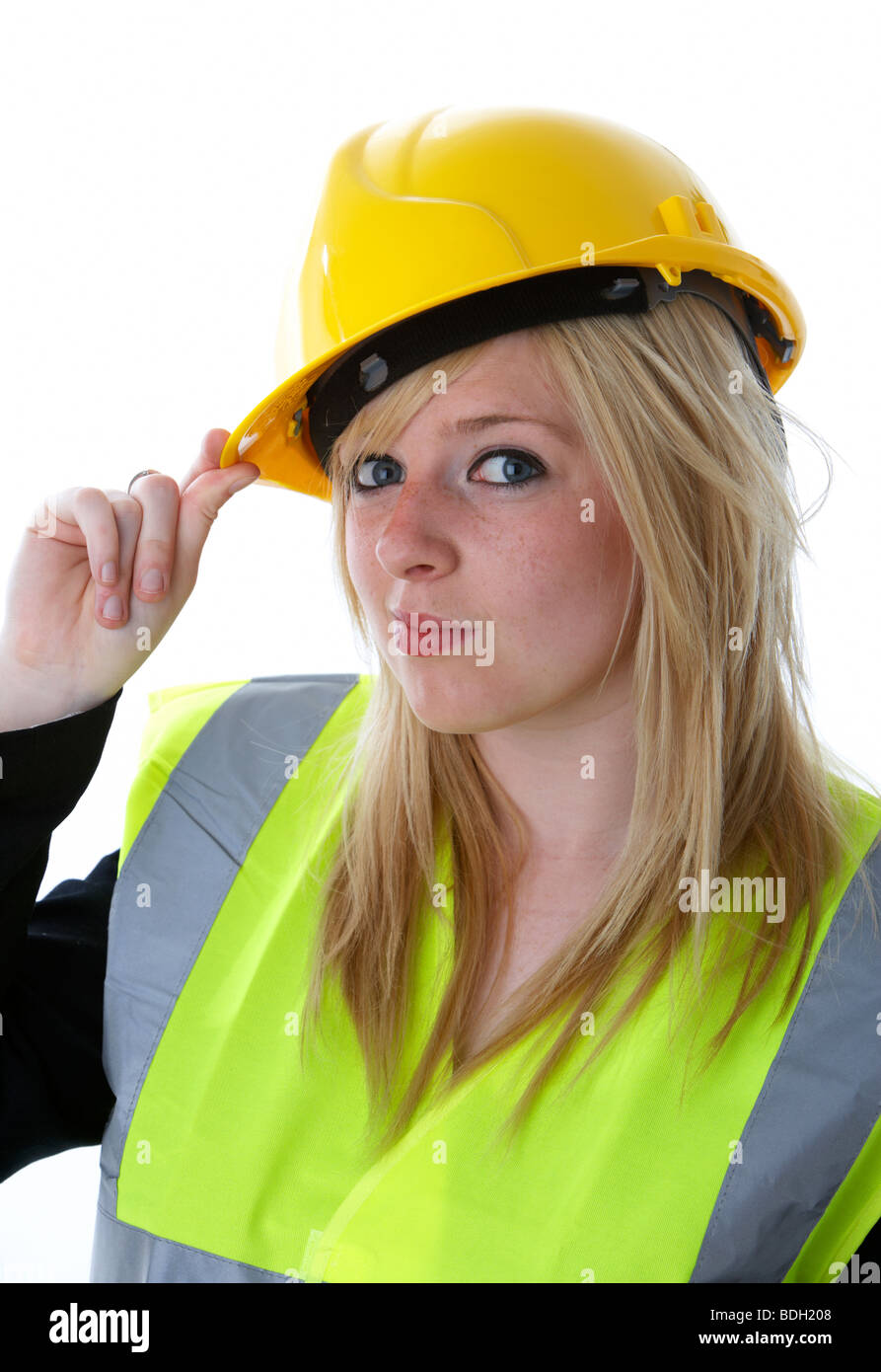 I giovani di 20 anni donna bionda indossare casco giallo e alta vis vest il ribaltamento il suo cappello con wry sorriso e con il contatto visivo Foto Stock