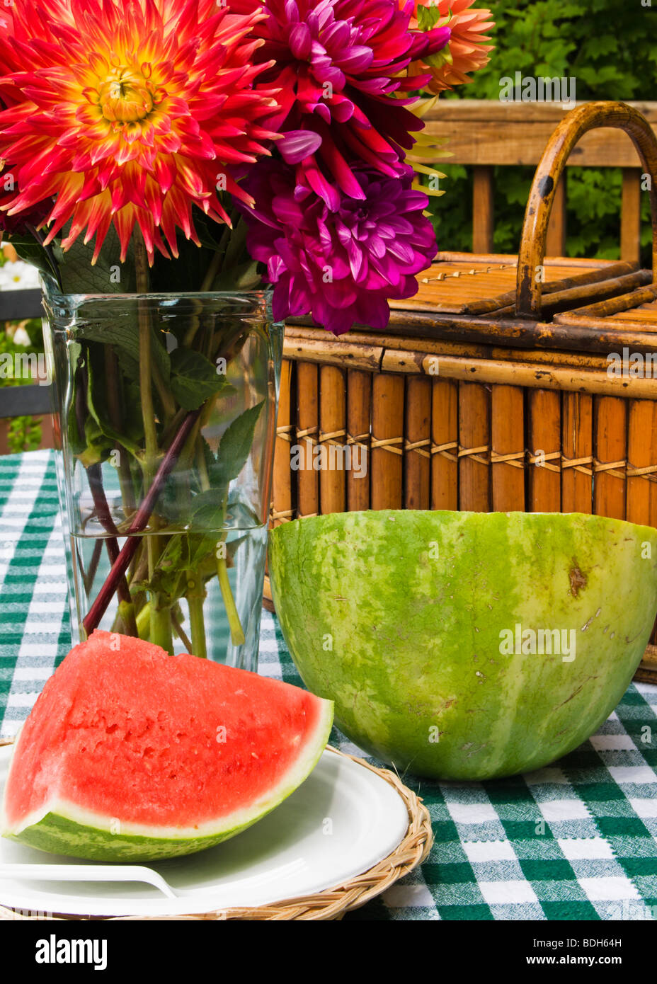 Anguria e un vaso di dalie su un tavolo da picnic con cestino pic-nic in  background Foto stock - Alamy