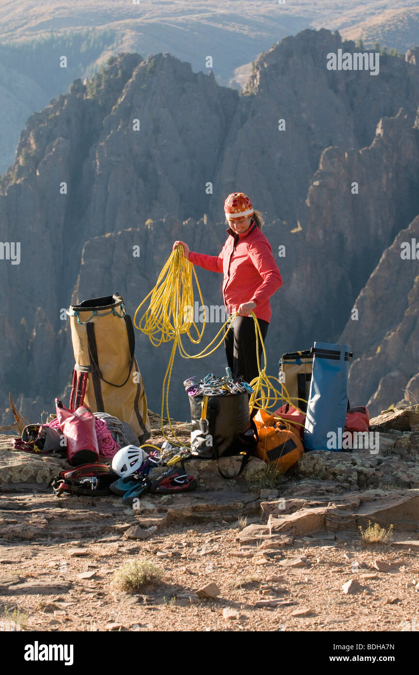 Una donna di avvolgimento di una corda di arrampicata accanto a sacchi multipli di marcia nelle montagne di Crawford, Colorado. Foto Stock