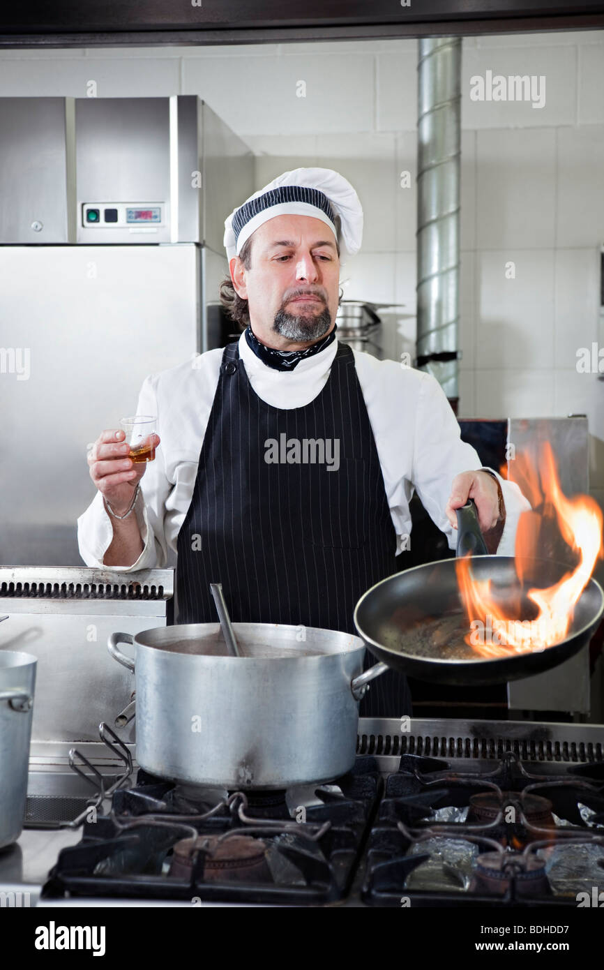 Maturo cuoco azienda pan e facendo flamb Foto Stock