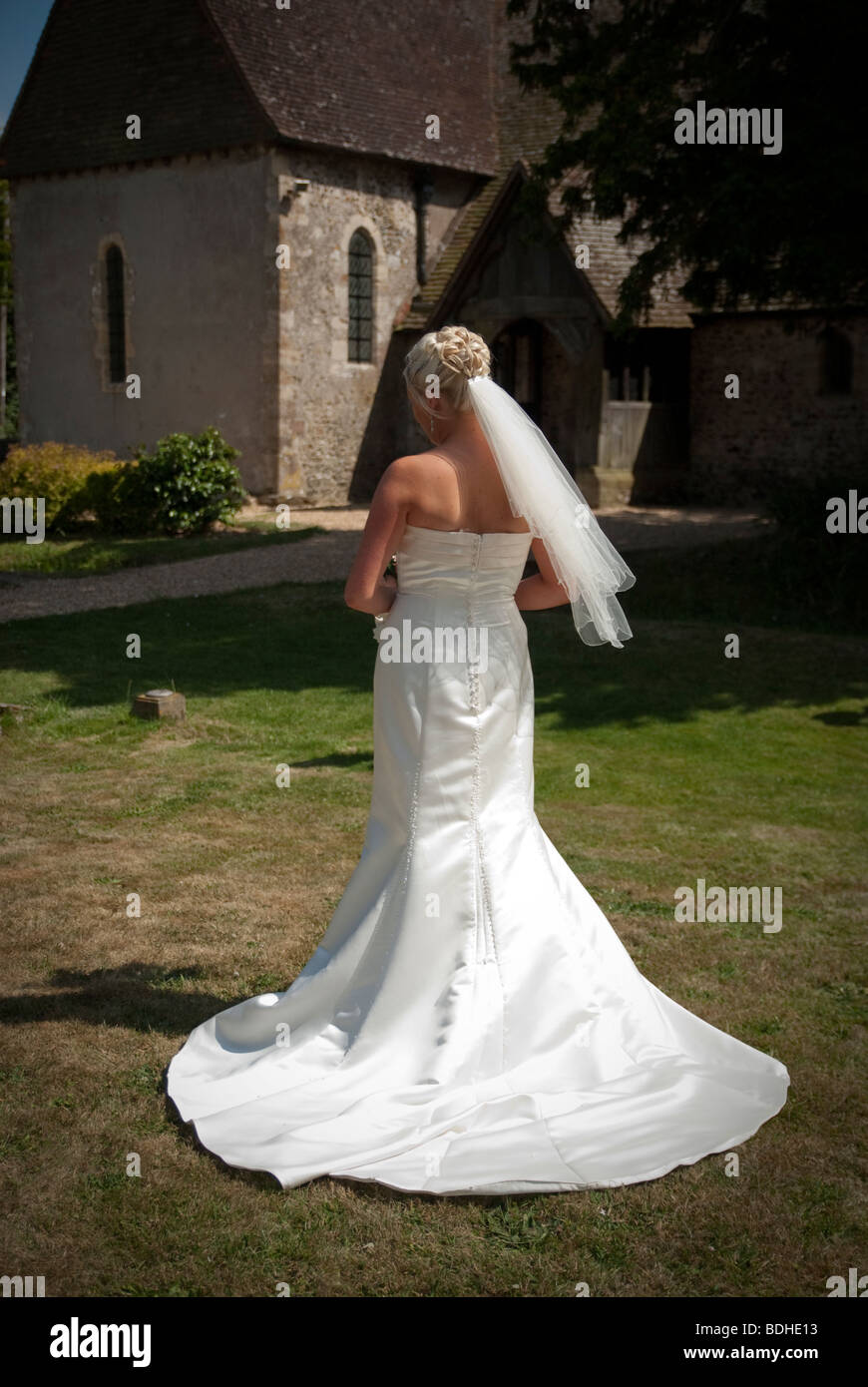 Sposa in piedi al di fuori di piccola chiesa torna alla telecamera volto invisibile Foto Stock