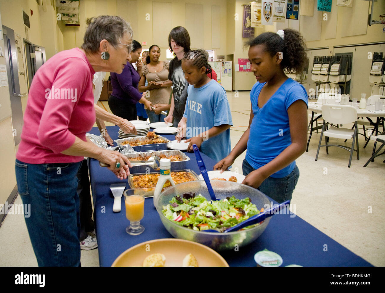 Selena Pina, una casa madre di quattro e i suoi bambini stare in linea per ricevere la cena preparata dai volontari della promessa di famiglia Foto Stock