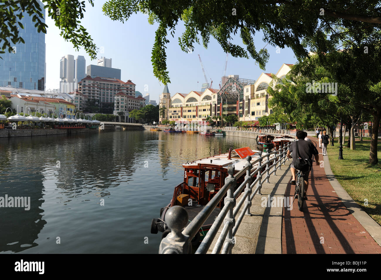 I ciclisti sulla passeggiata sulla riva del Fiume Singapore, Singapore Foto Stock