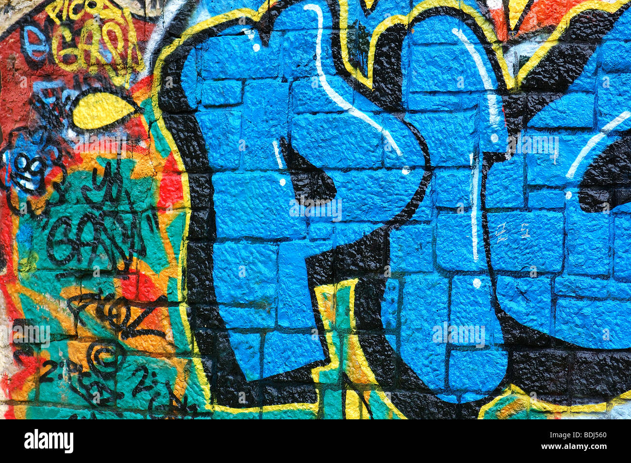 Parete ruvida superficie coperta con colorati graffiti. Urban street art background. Foto Stock