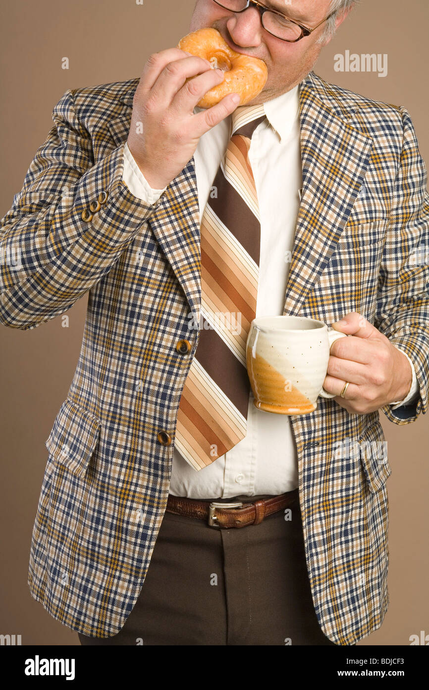 Imprenditore retrò mangiando una ciambella e bere una tazza di caffè Foto Stock