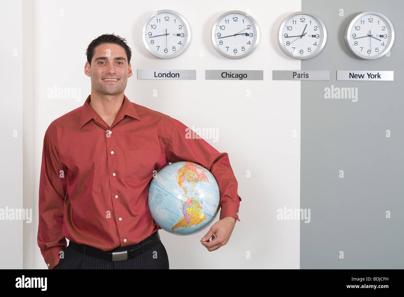 Imprenditore Globo tenuta in piedi da orologi che mostra fusi orari internazionali Foto Stock