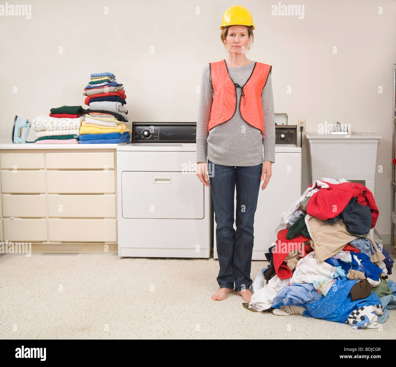 Donna che indossa Giubbotto di sicurezza e di elmetto facendo il servizio lavanderia Foto Stock