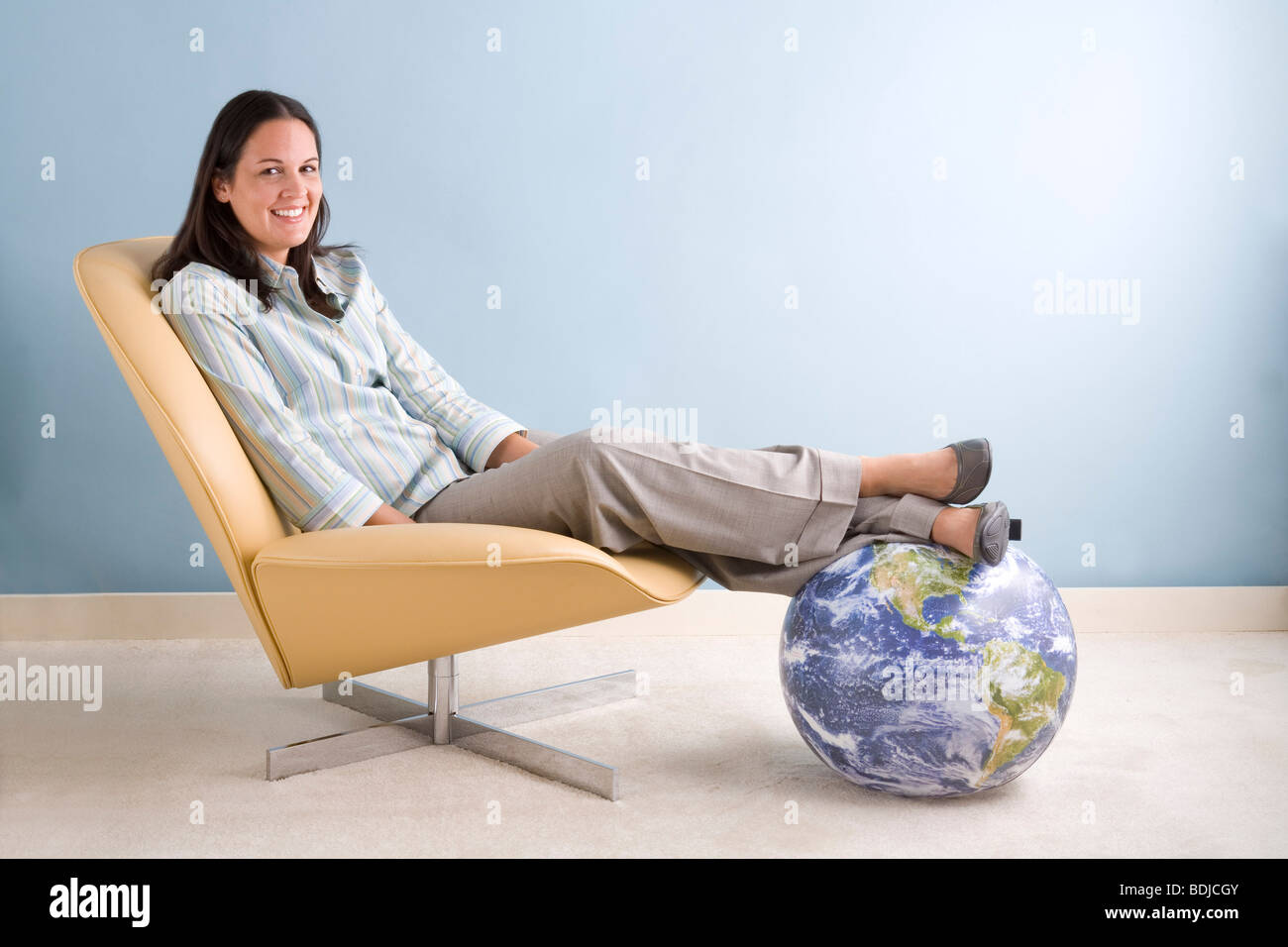 Imprenditrice seduta con i suoi piedi su un globo Foto Stock