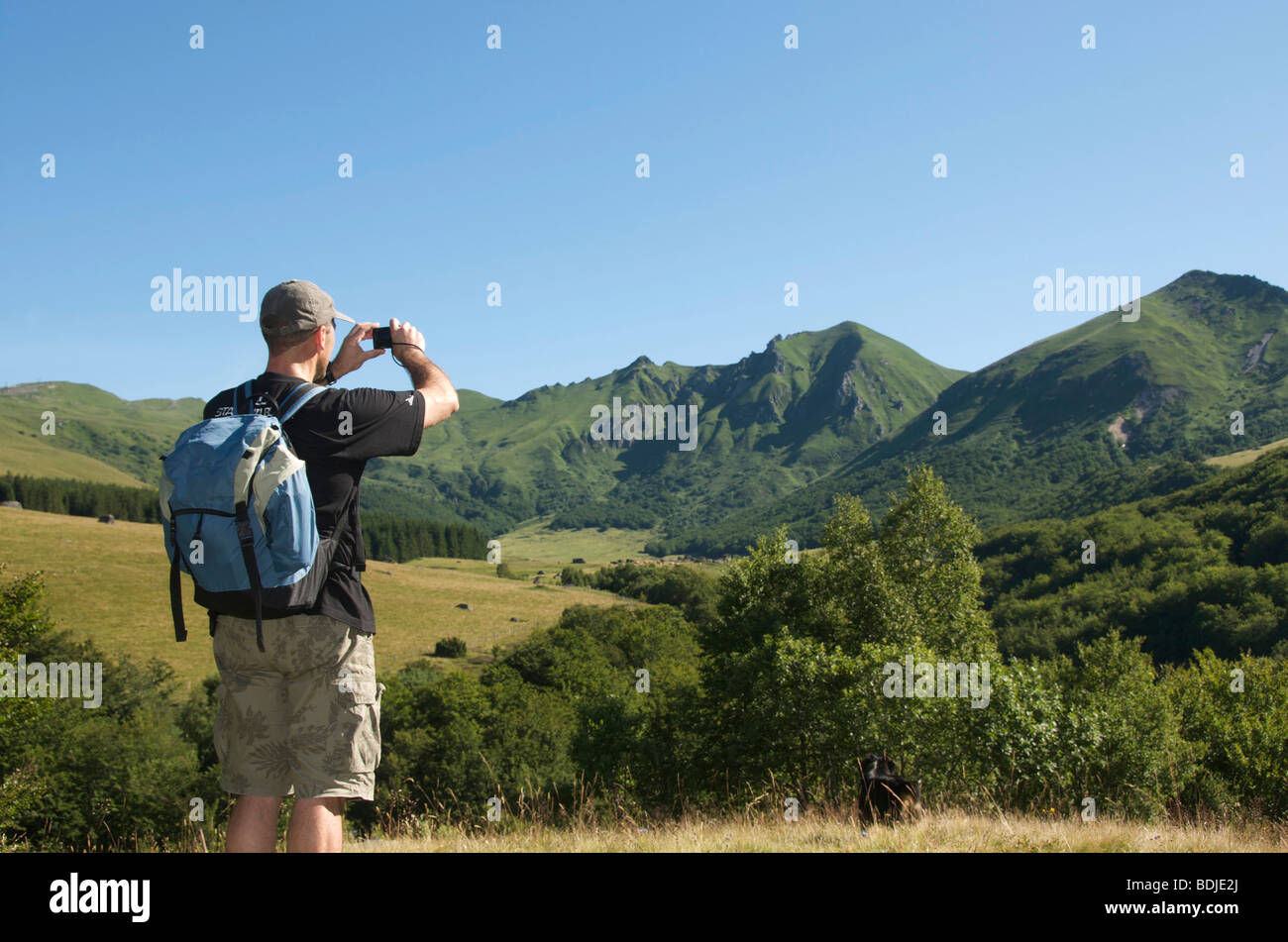 Escursionista / walker nel Massif du Sancy, Auvergne, Francia - prendendo una foto del paesaggio. Foto Stock