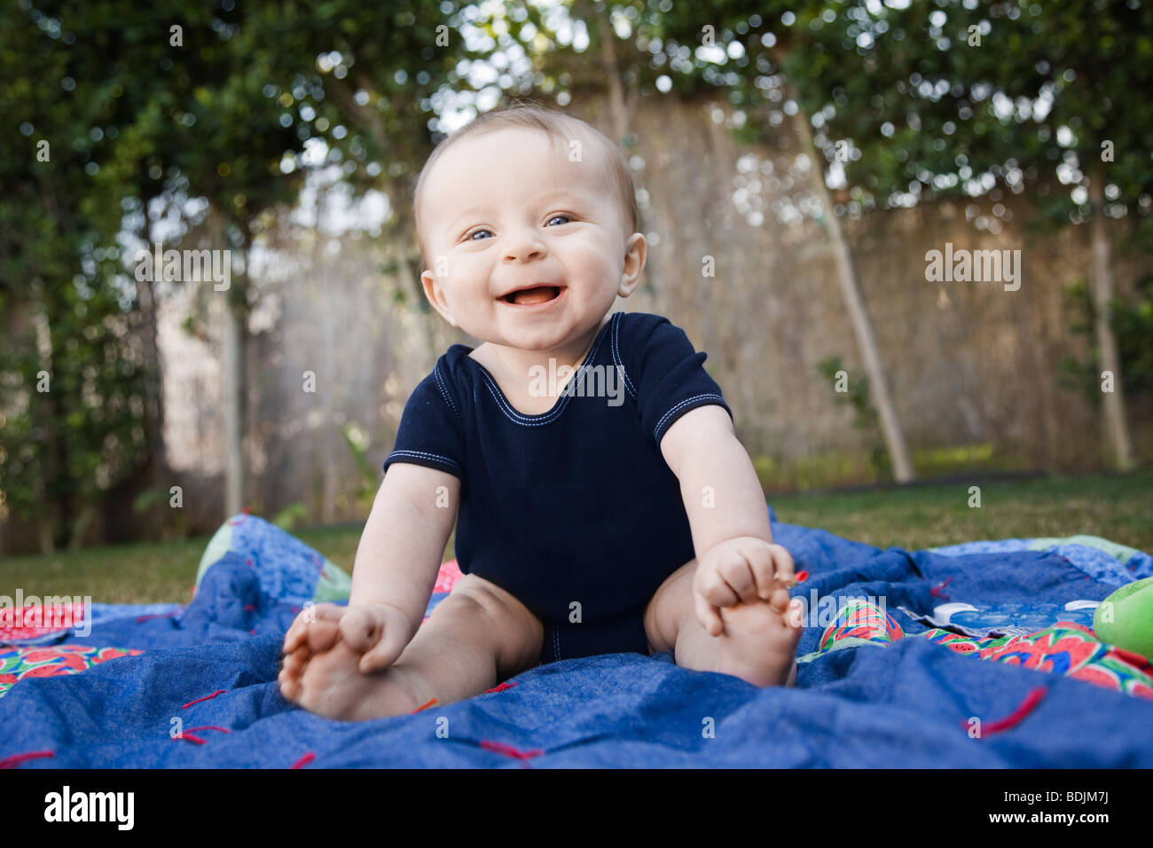 Baby sitting su una coperta al di fuori Foto Stock