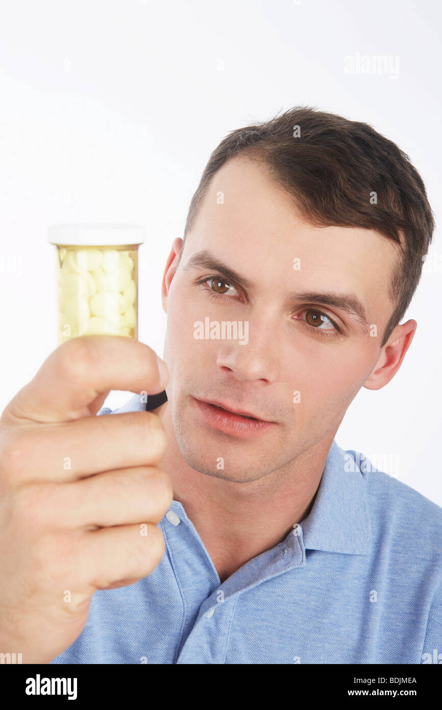 Uomo che guarda un flacone di pillole Foto Stock