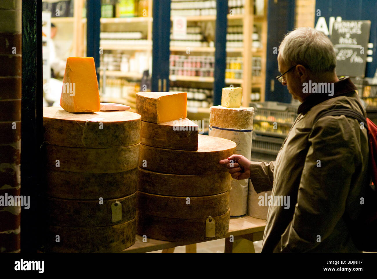 Uomo che guarda truckles di formaggio al di fuori Neal's Yard, Borough Market, Londra al crepuscolo. Foto Stock