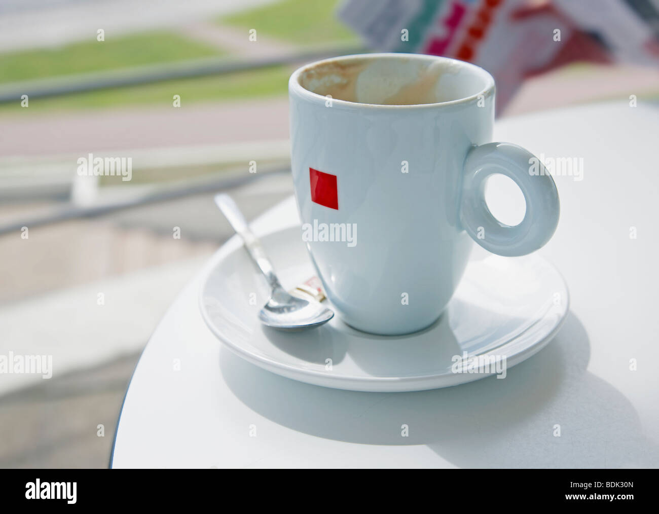 Tazza vuota di caffè si siede sul tavolo bianco nella luce del sole Foto Stock