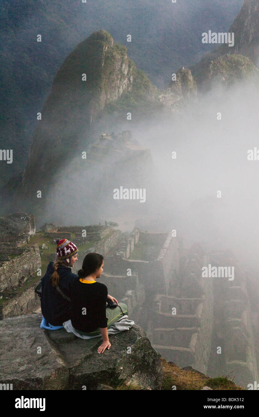 Turisti in antiche rovine di Machu Picchu in montagna Ande in early morning mist, Perù Foto Stock