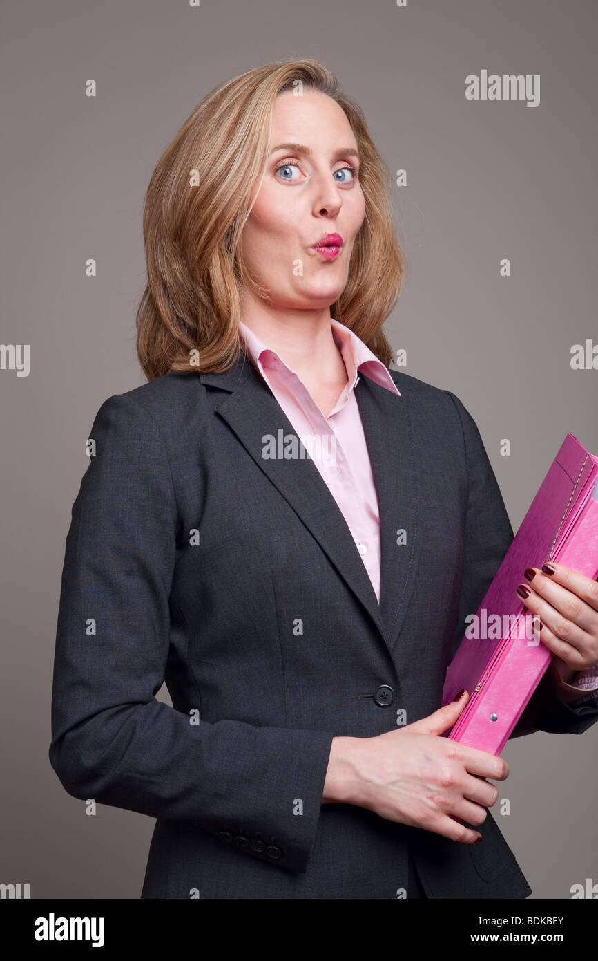 Imprenditrice con espressione cheeky portante nella cartella rosa Foto Stock