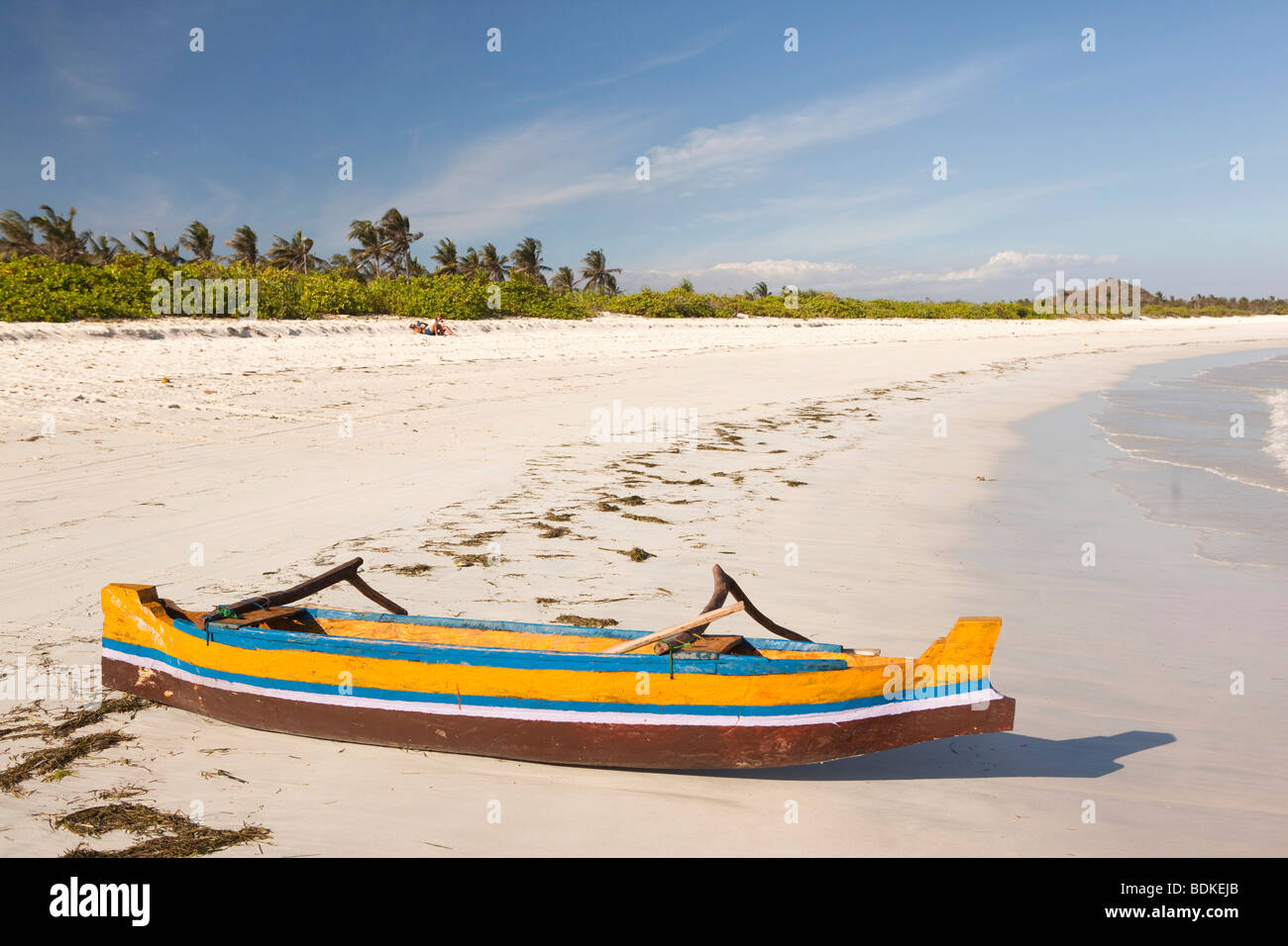 Indonesia, Lombok, Tanjung, spiaggia, giallo e blu dipinto di piroga barca da pesca spiaggiata sulla riva Foto Stock