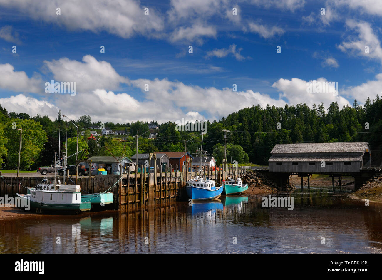 Ponte coperto e molo con barche a bassa marea in St Martins Baia di Fundy New Brunswick canada Foto Stock