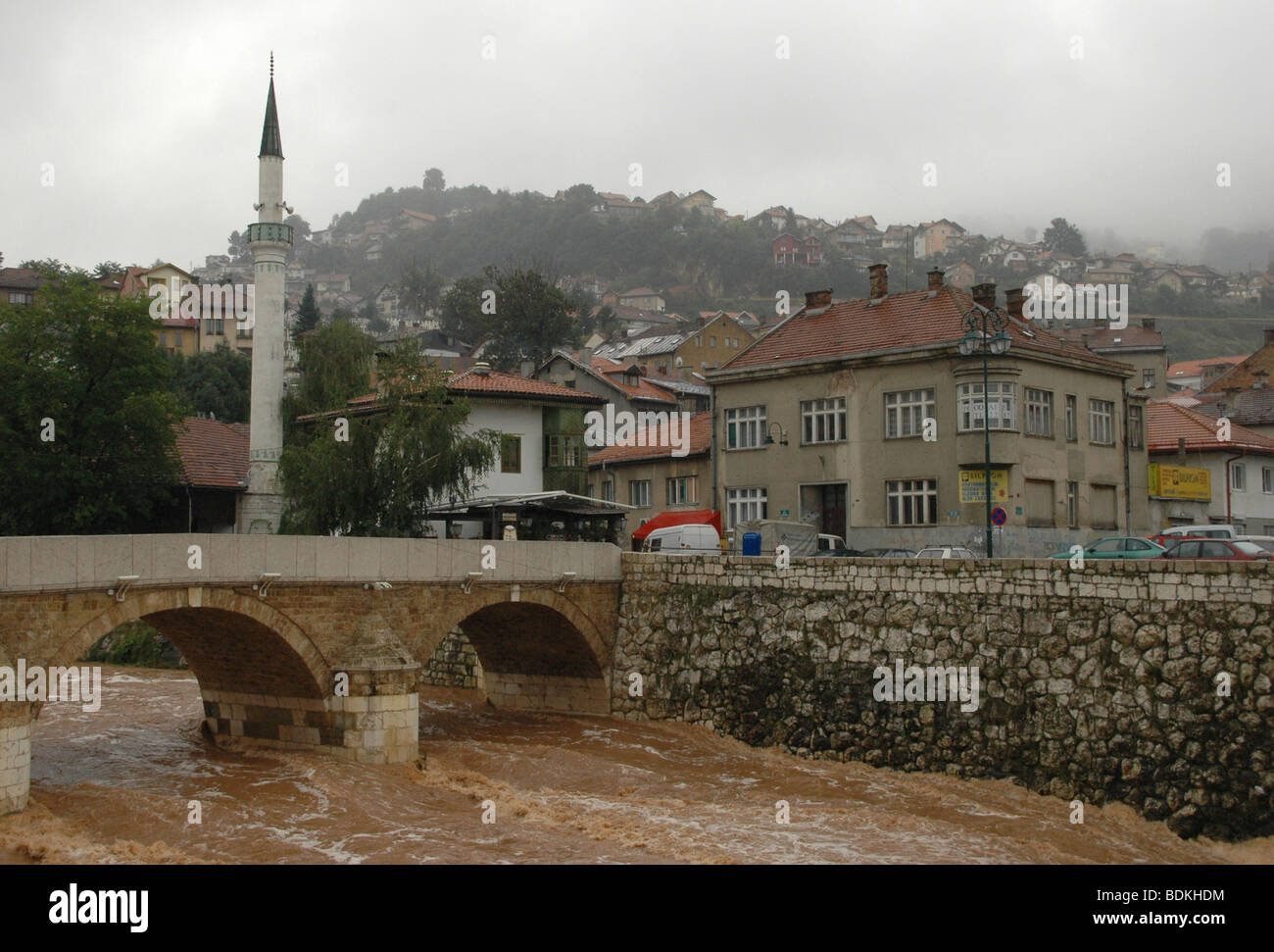 Una vista case, un minareto musulmano e di un ponte sul fiume Miljacka, nella città di Sarajevo in Bosnia ed Erzegovina. Foto Stock