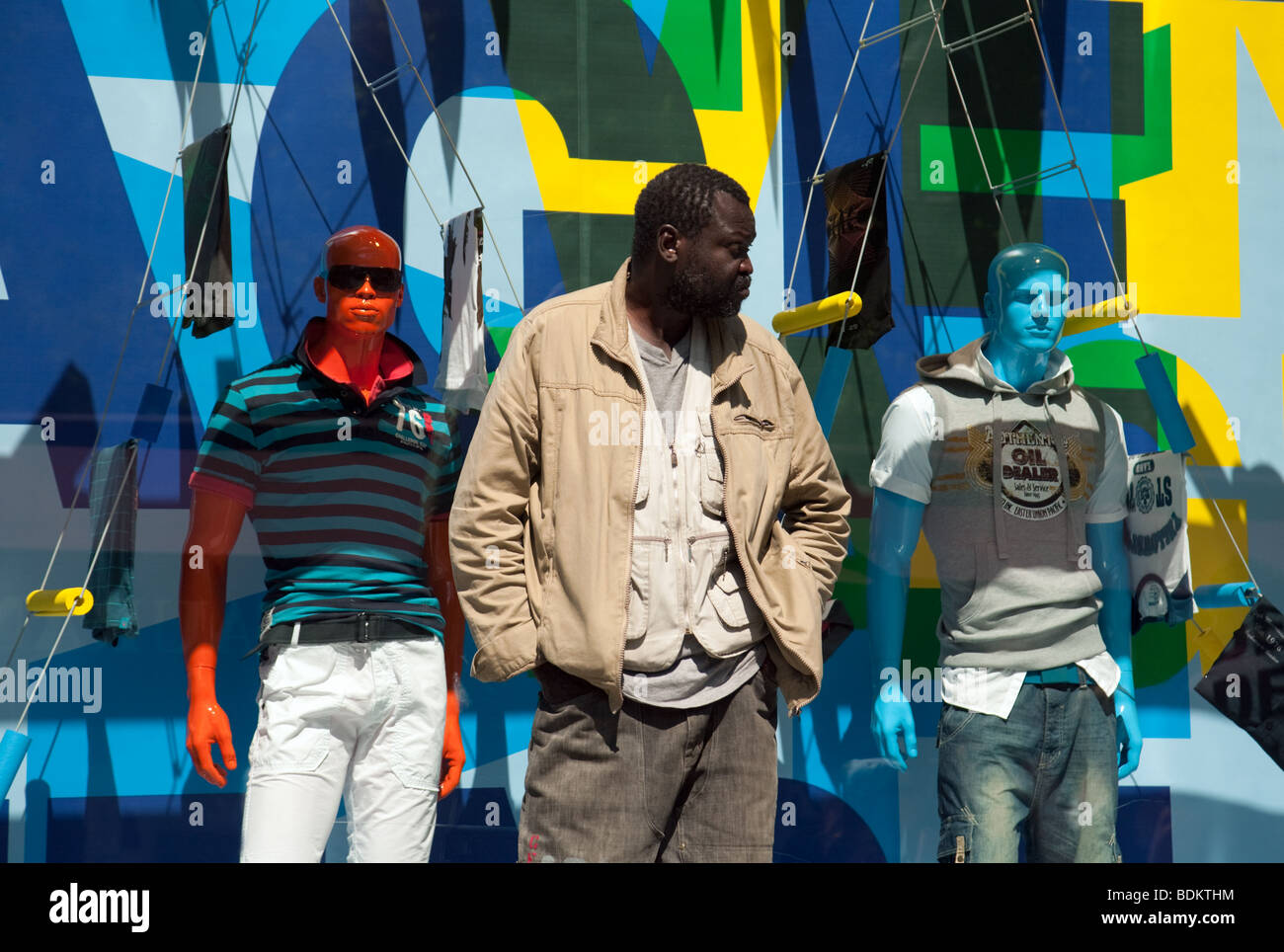 Moda uomo; Un uomo nero sta davanti a due manichini in una vetrina, Parigi, Francia; concetto diversità Foto Stock
