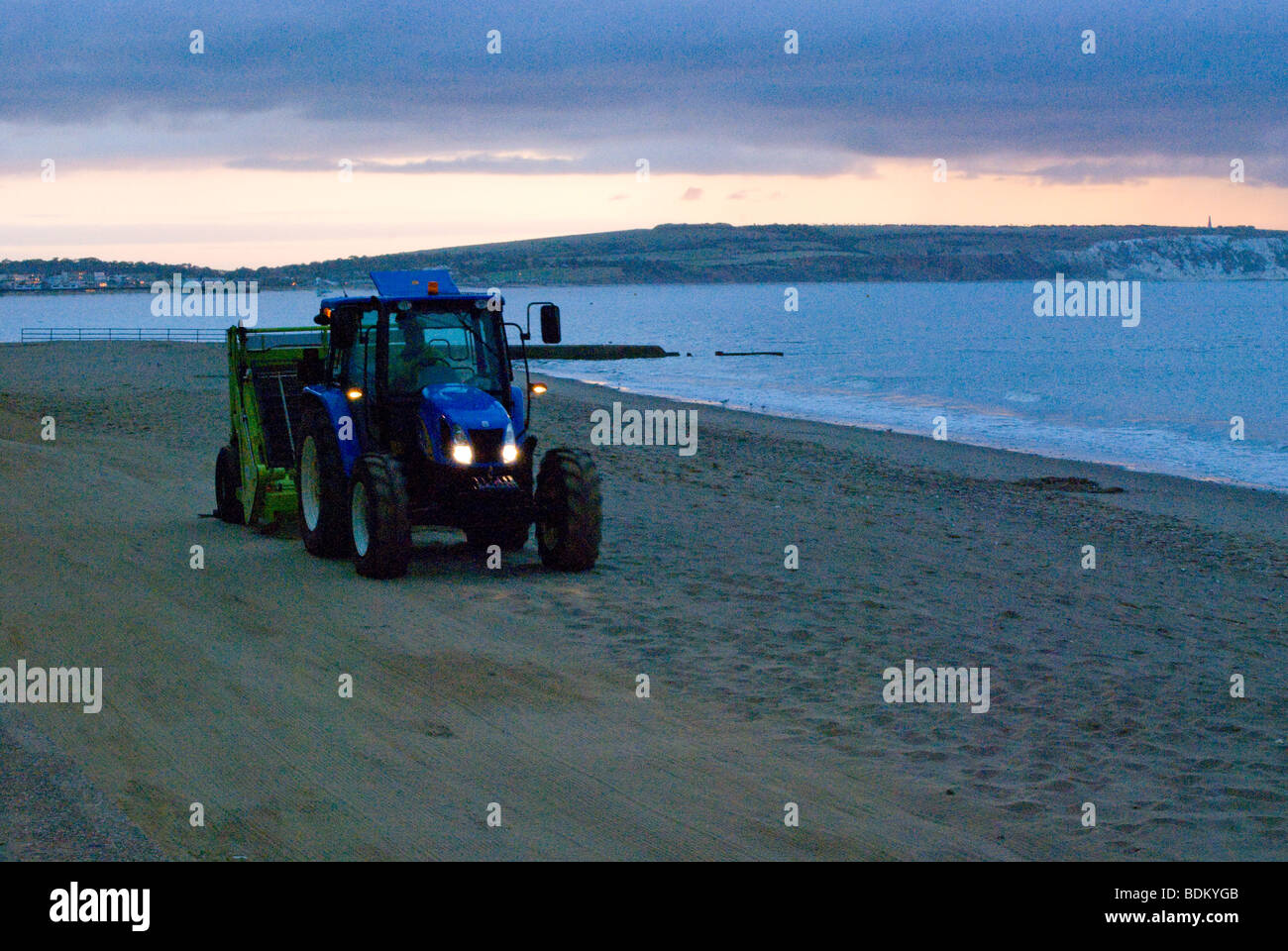 Un trattore la pulizia della spiaggia poco dopo l'alba a piccola speranza Beach, Isle of Wight UK. Foto Stock