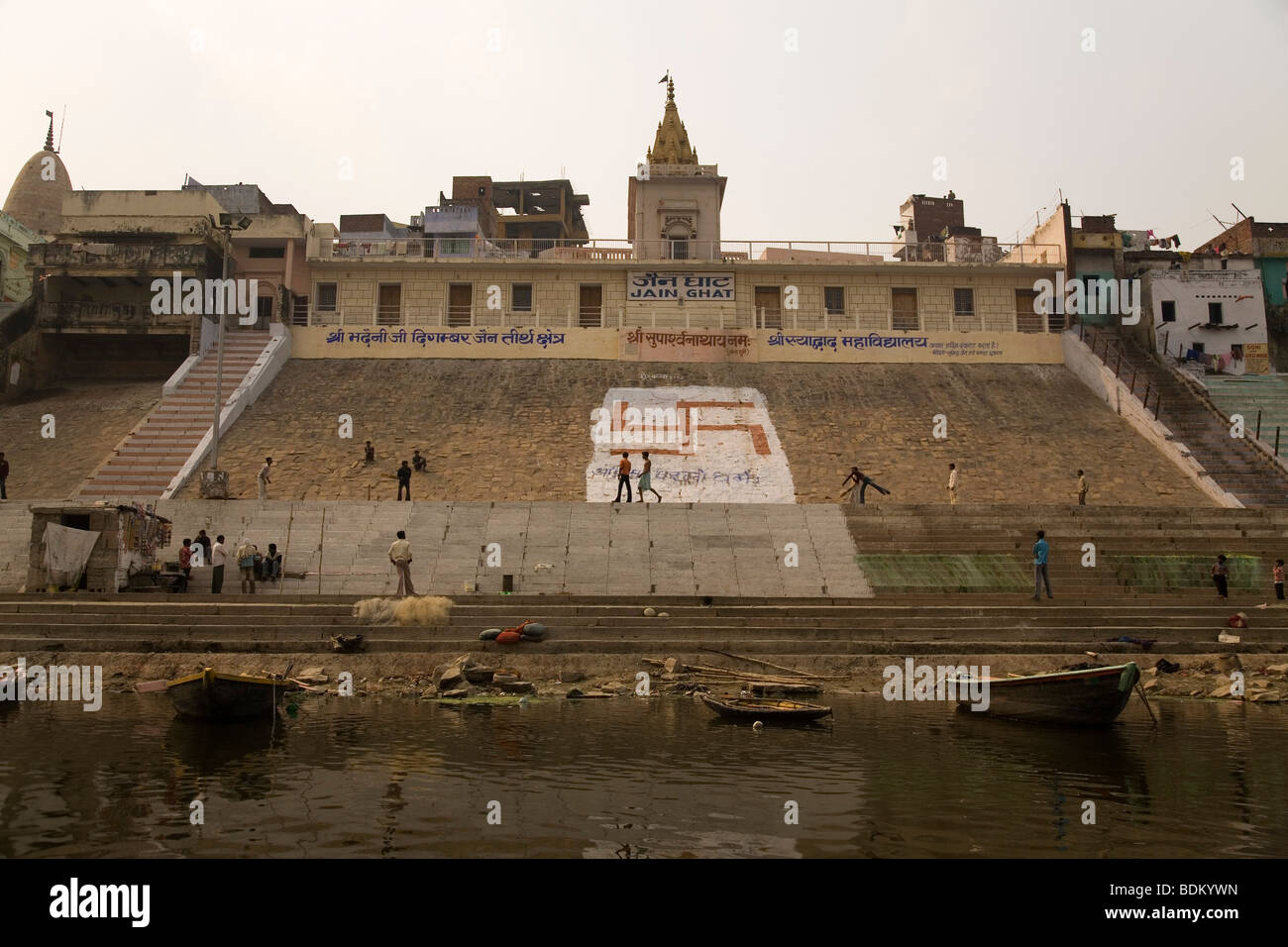 La Ganga (Gange) fiume lambisce le rive del Jain Ghat di Varanasi (India). Una svastica adorna i ghats. Foto Stock