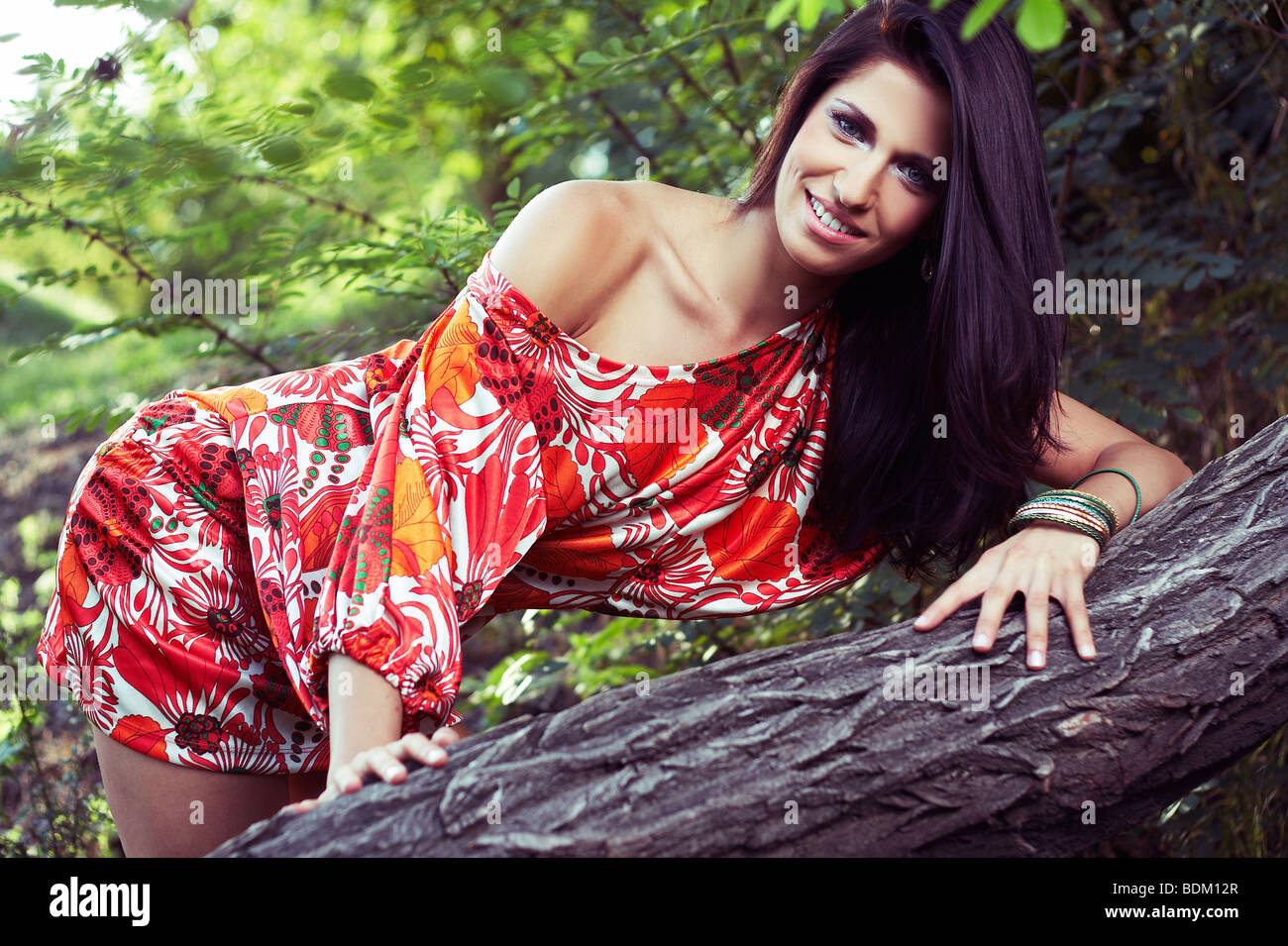 Bella ragazza seduta su erba in bello e colorato vestito Foto Stock