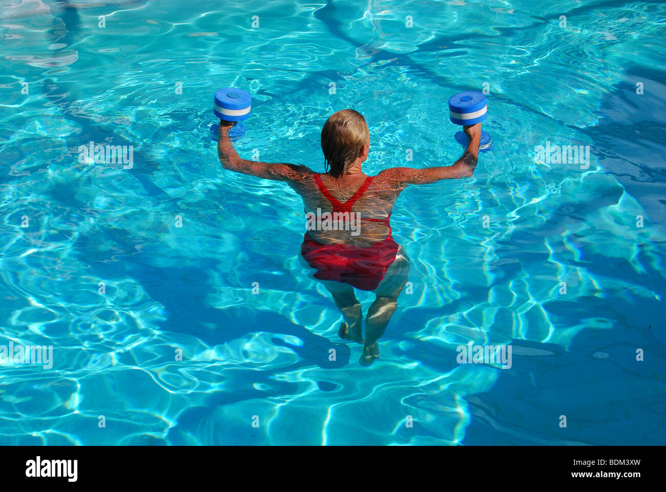 Adulto sano donna esercizi con i pesi in piscina Foto Stock