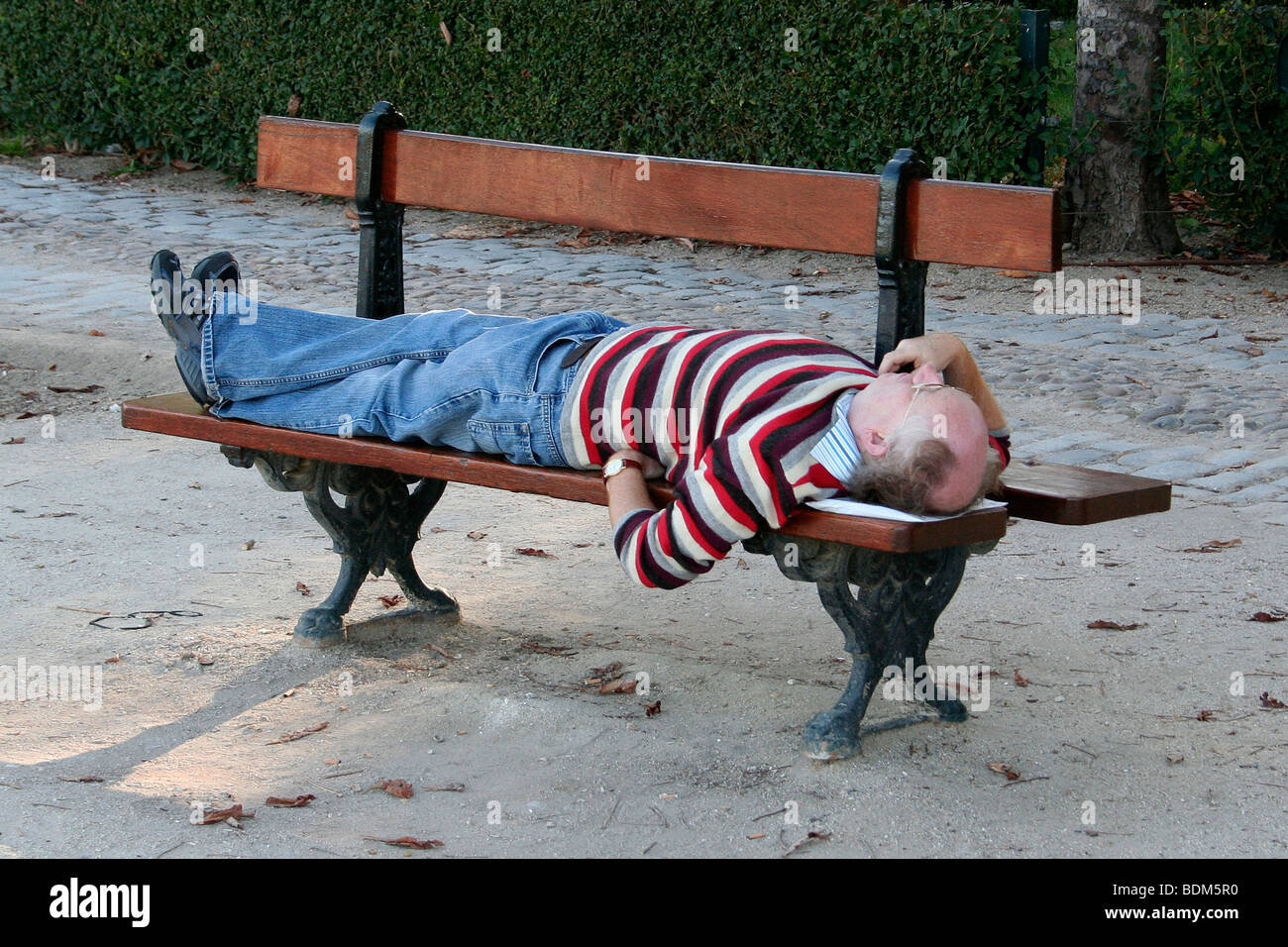 Prendendo una siesta su una panchina nel parco del Retiro di Madrid Foto Stock