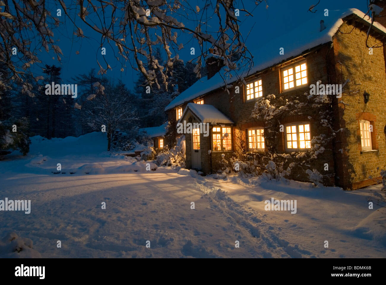 Scena di natale del cottage del paese come la notte inizia a cadere circondato dalla neve Foto Stock