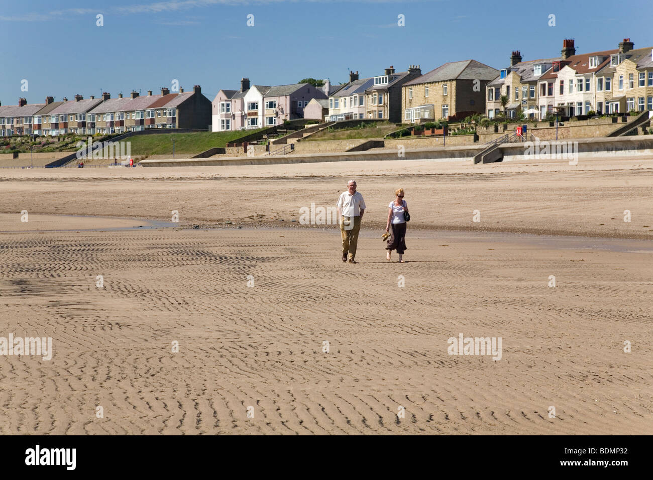 Una coppia in pensione a piedi sulla spiaggia di Newbiggin-per-il-mare in Northumberland, Inghilterra. Foto Stock