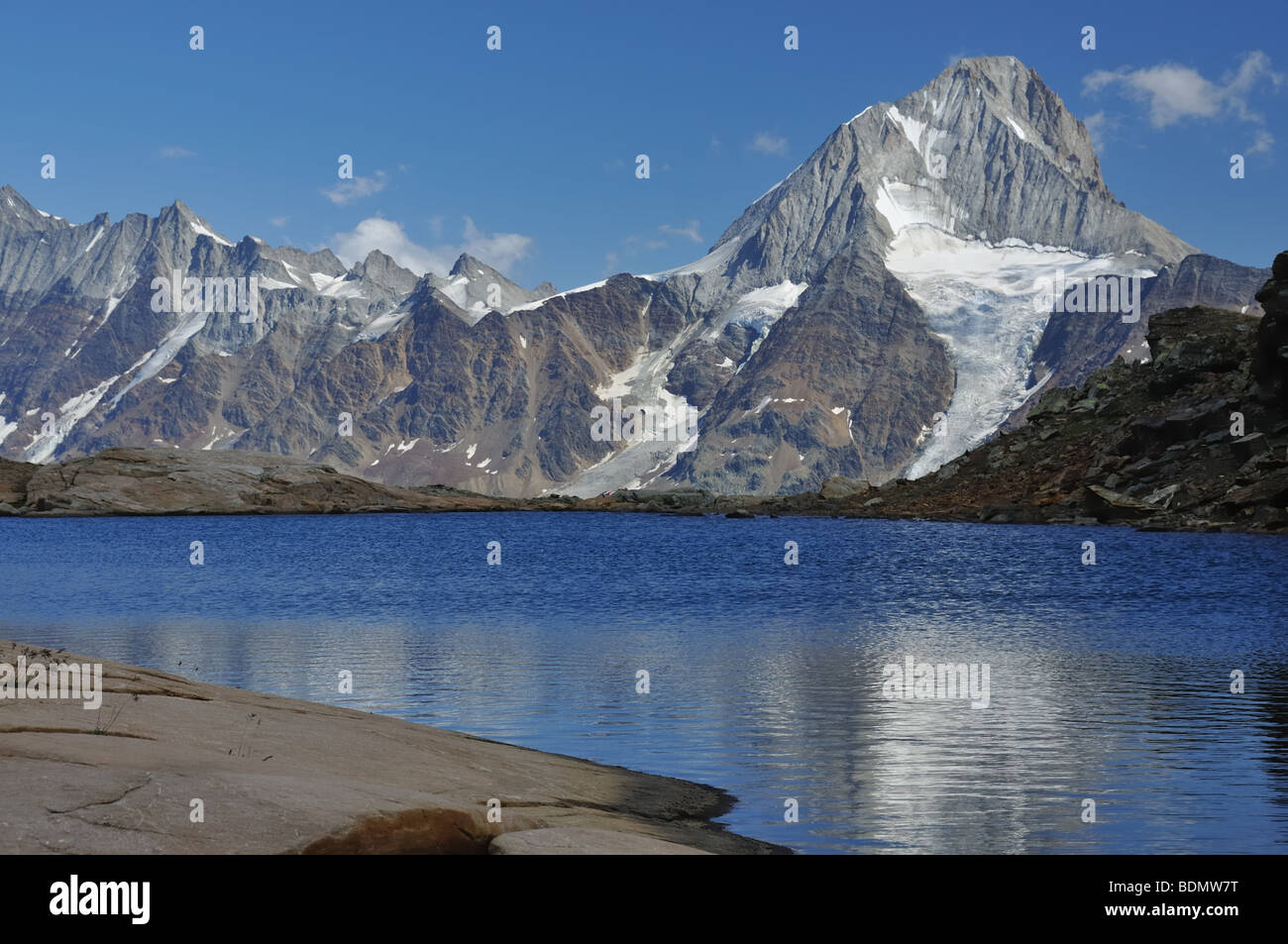 La riflessione di un elevato picco con il ghiacciaio in un lago di montagna Foto Stock