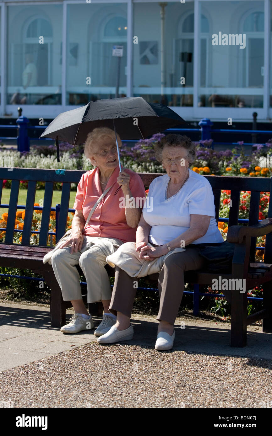 Due donne riparo sotto un ombrello a Eastbourne, Inghilterra. Foto Stock