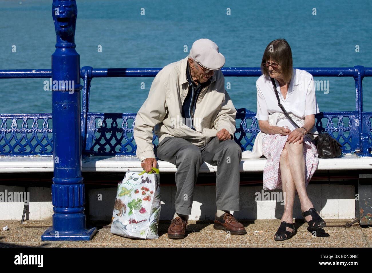 Una coppia di anziani sedersi sul molo a Eastbourne, Inghilterra. Foto Stock