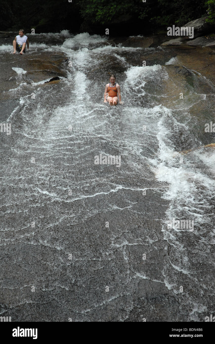 Una persona giovane scorre giù un sasso piatto scorrevole di acqua nella Carolina del Nord. Foto Stock